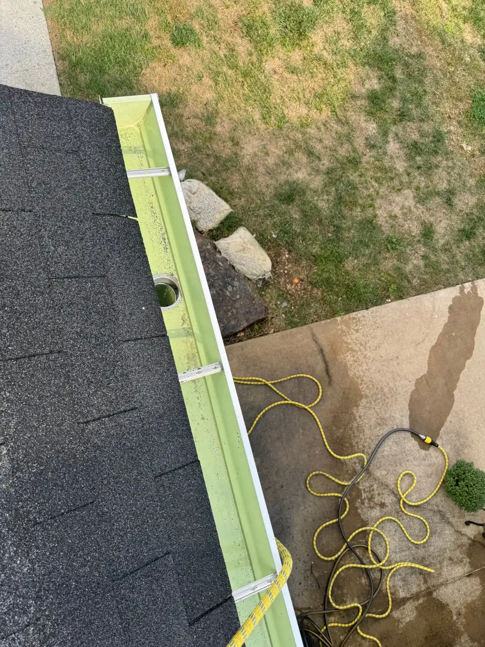 Clean gutter run with downspout outlet and hidden hangers along an asphalt shingle roof edge in Chesterfield, MO
