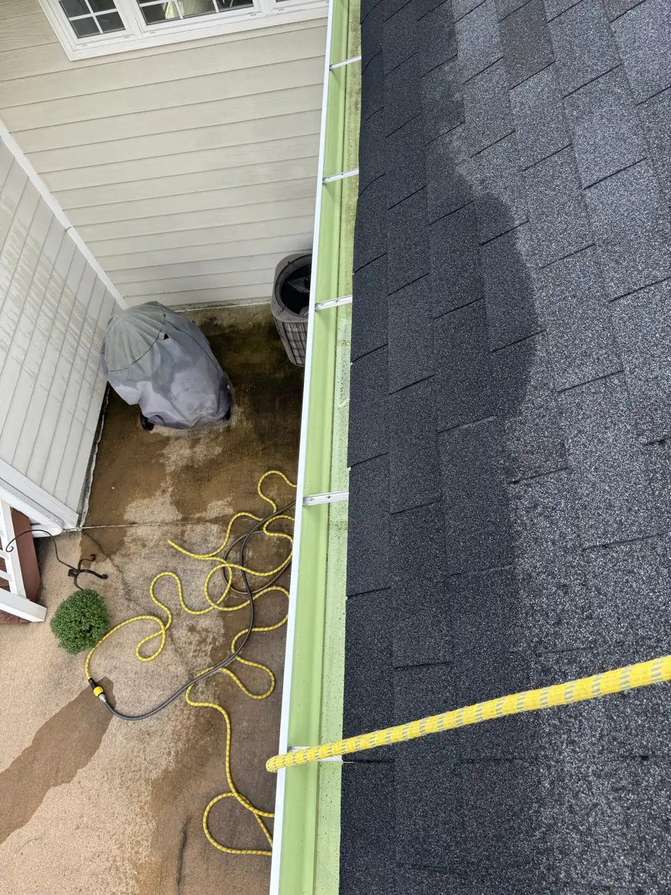 Long gutter run cleaned out above a patio, viewed from the roof in Chesterfield, MO